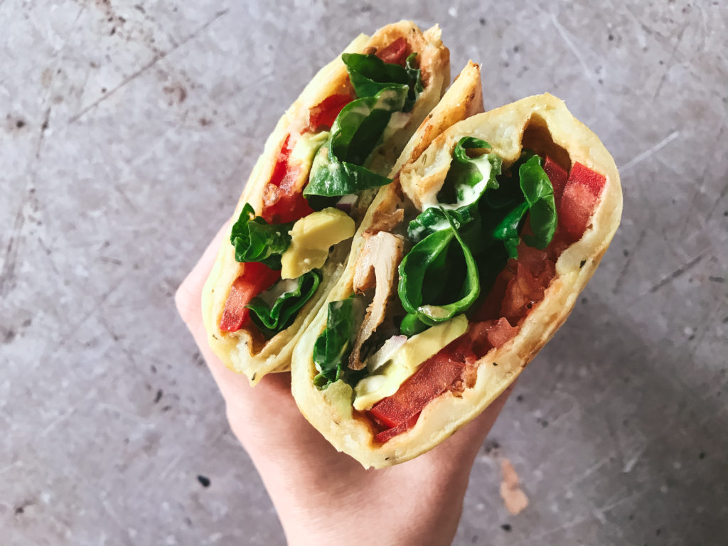 Wrap de patata enrollado sobre sí mismo y relleno con tomate, espinacas, cebolla, aguacate, no-pollo vegano y salsa de anacardos estilo César.