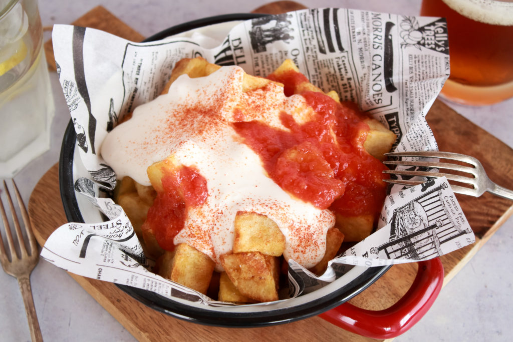 Patatas fritas en dados servidas con veganesa y salsa de tomate picante, decoradas con pimentón