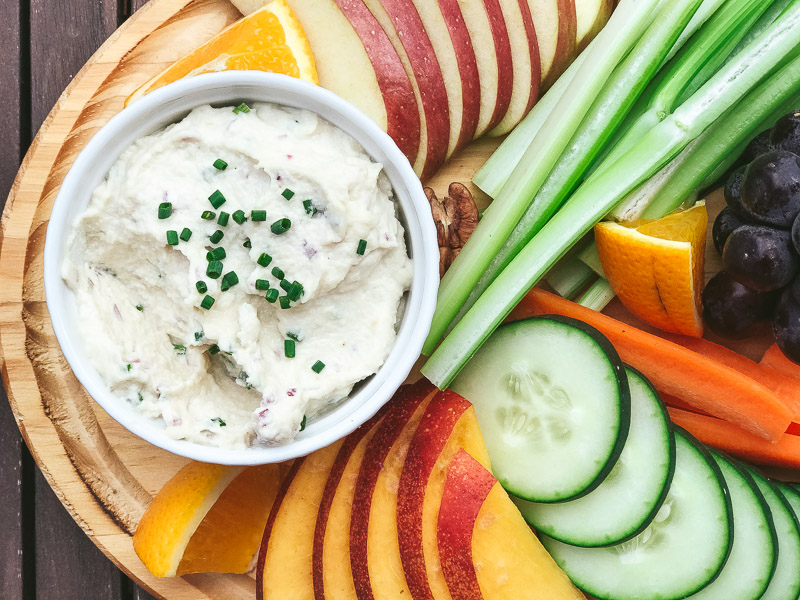 Dip de anacardos en una tabla con crudites de fruta y verduras