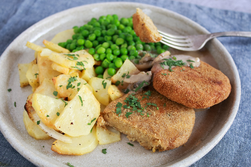 Filetes rusos acompañados de salsa de champiñones, guisantes y patatas asadas