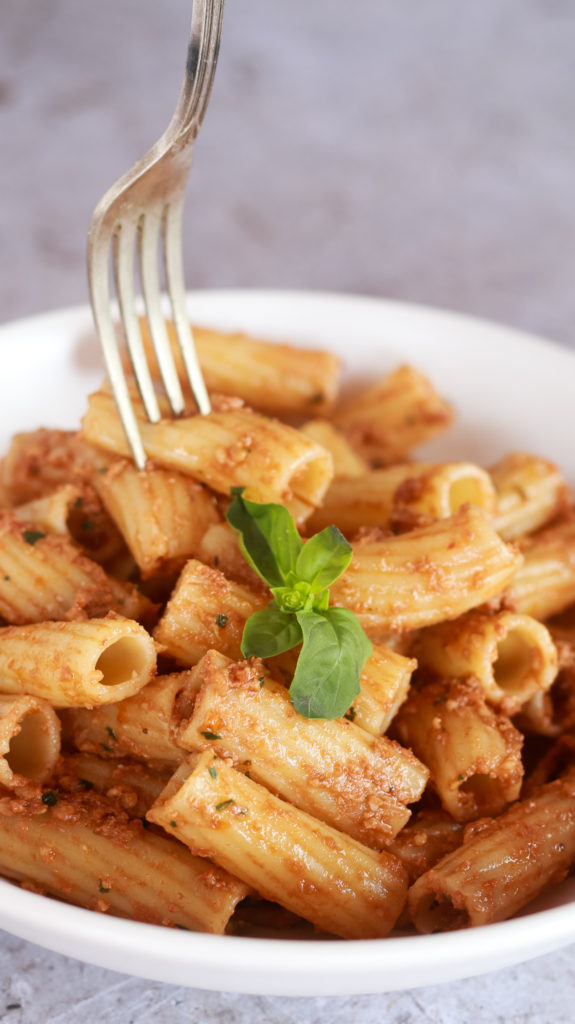 Primer plano de la pasta con pesto rosso con un tenedor pinchando los tortiglioni