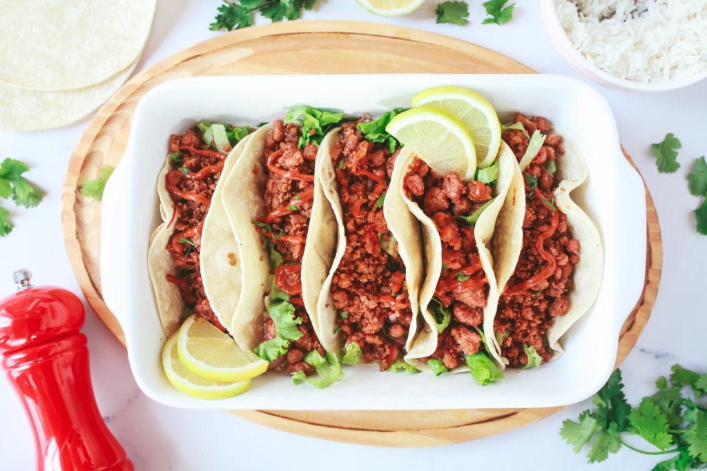 Tacos en una bandeja rellenos con picadillo vegano y salsa