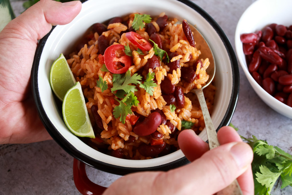 Arroz con alubias y tomate decorado con cilantro, guindilla y lima