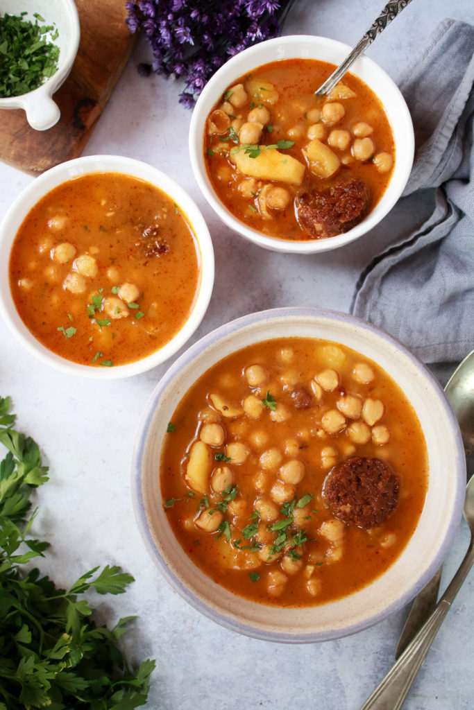 Tres platos hondos con el guiso de garbanzos y chorizo vegano